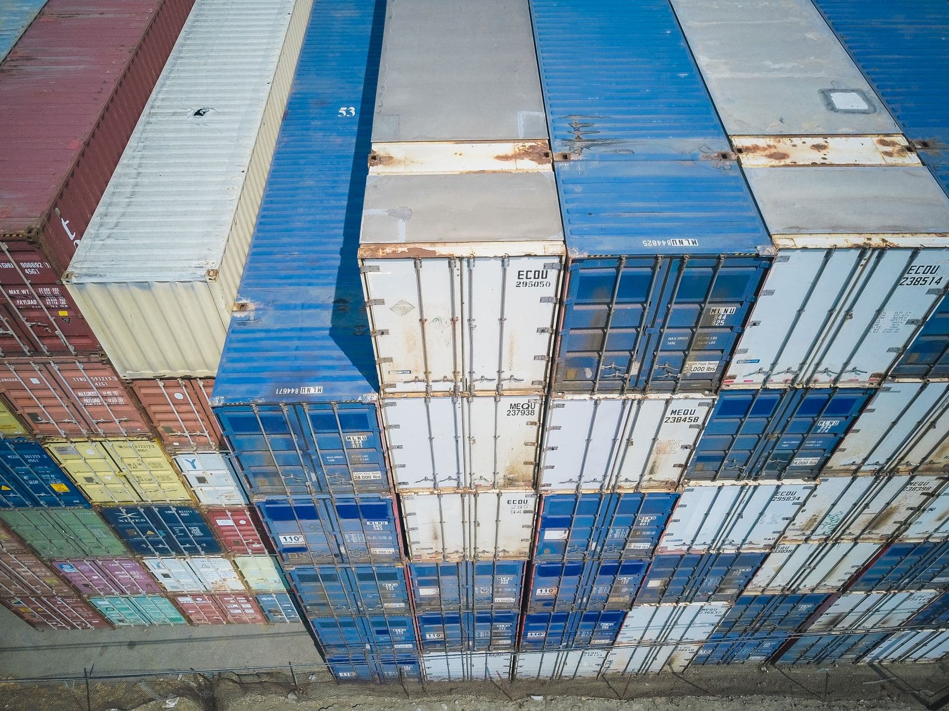 Aerial view of stacked shipping containers with visible ID codes