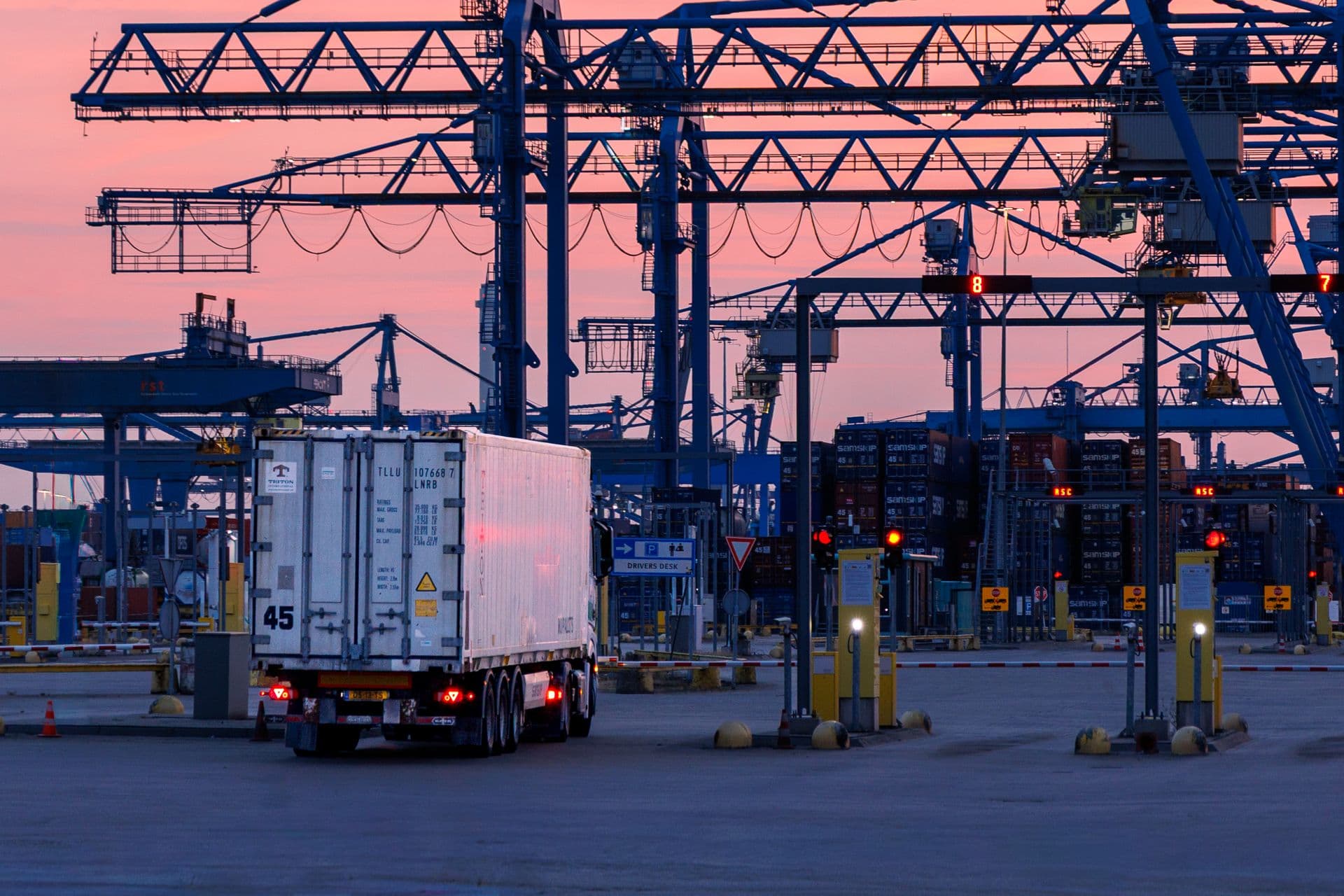 Truck departing a container terminal gate at sunset